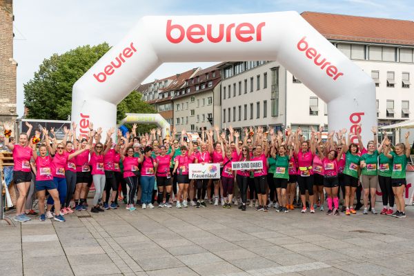 Eine große Frauengruppe steht zum Beurer Frauenlauf vor einem großen Banner, auf dem das Beurer Logo mehrfach abgebildet ist.