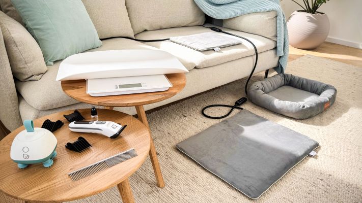 Das Bild zeigt ein Sofa mit Tischen und Teppich. Darauf sind die sechs neuen „Love Your Pet by beurer“ Produkte zu sehen.