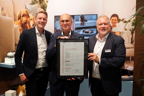 Das Bild zeigt drei Männer in Anzügen mit einer Urkunde.