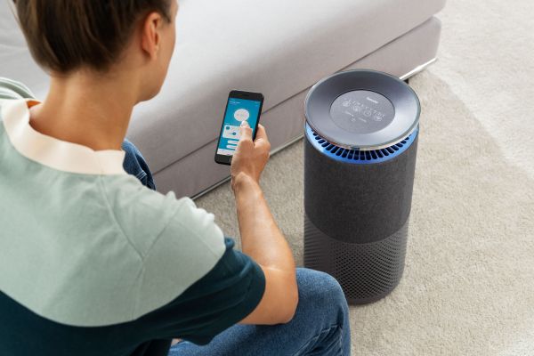 Eine Frau steuert per Smartphone den Luftreiniger Beurer LR 401.