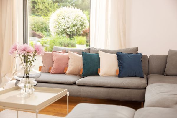 Das Akku-Heizkissen HK 77 „Heaty" liegt in sechs Farbtönen auf einem Sofa.