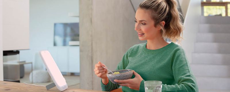 Beurer Tageslichtlampe TL 35 - Anwendungsbild Frau sitzt vor Tageslichtlampe