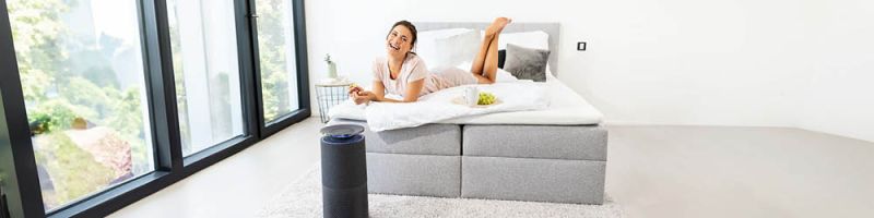 Junge Frau entspannt auf dem Bett und Beurer Luftreiniger LR 401 steht im Vordergrund
