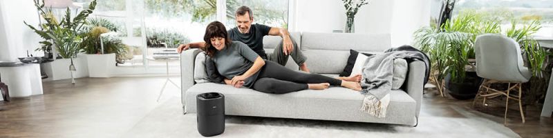 Paar mittleren Alters liegt auf der Couch und Beurer Luftbefeuchter LB 200 steht im Vordergrund