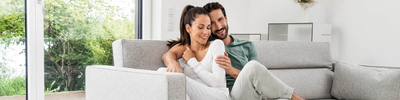 Eine Frau und ein Mann sitzen angeschmiegt auf einer Couch