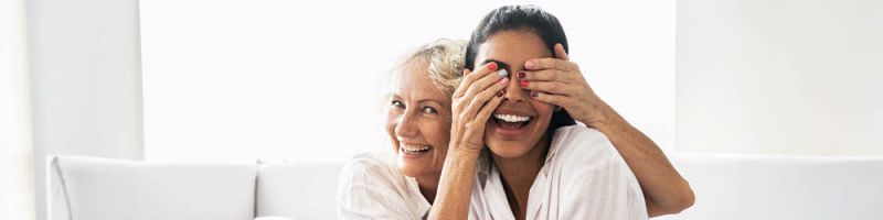 Eine ältere Frau hebt einer anderen die Augen zu und zeigt ihre lackierten Nägel - sie haben Spaß