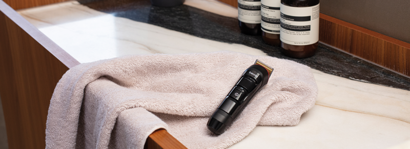 Der Bart Trimmer MN4X von Beurer liegt auf einem Handtuch auf einer Ablage im Badezimmer