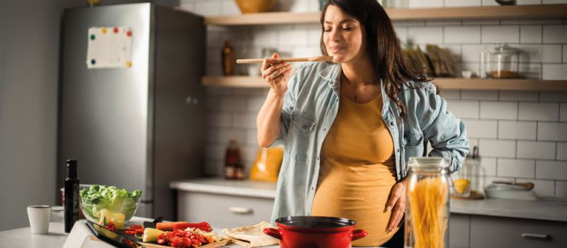 Schwangere Frau kocht in der Küche mit frischen Lebensmitteln