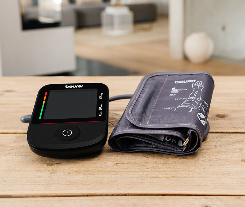 Beurer BM 48 Blutdruckmessgerät liegt auf Holztisch im Wohnzimmer