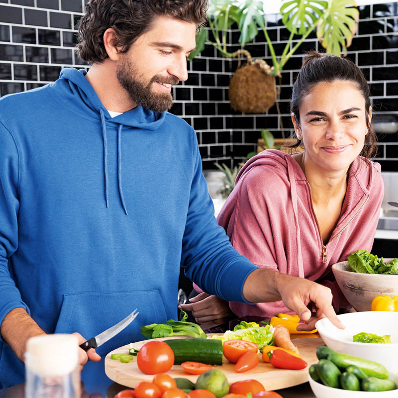 Mann und Frau bereiten gemeinsam frisches Gemüse in einer modernen Küche zu und lachen dabei 