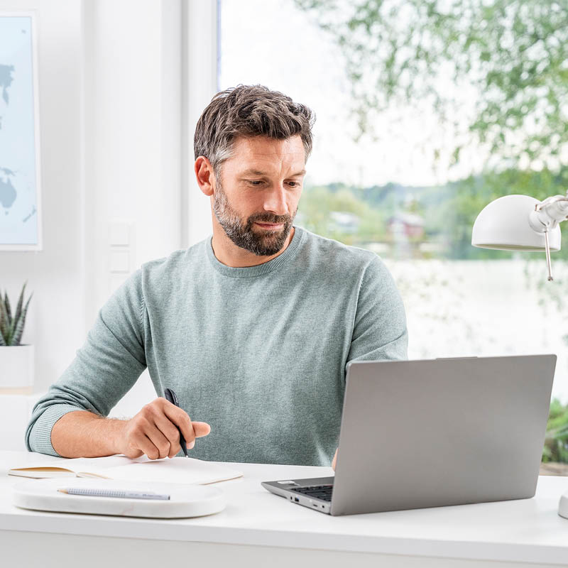 Ein Mann mittleren Alters sitzt am Schreibtisch und arbeitet an seinem Laptop