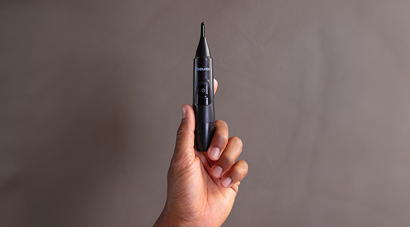 Hand hält den Beurer Präzisionstrimmer MN2X vor neutralem Hintergrund 