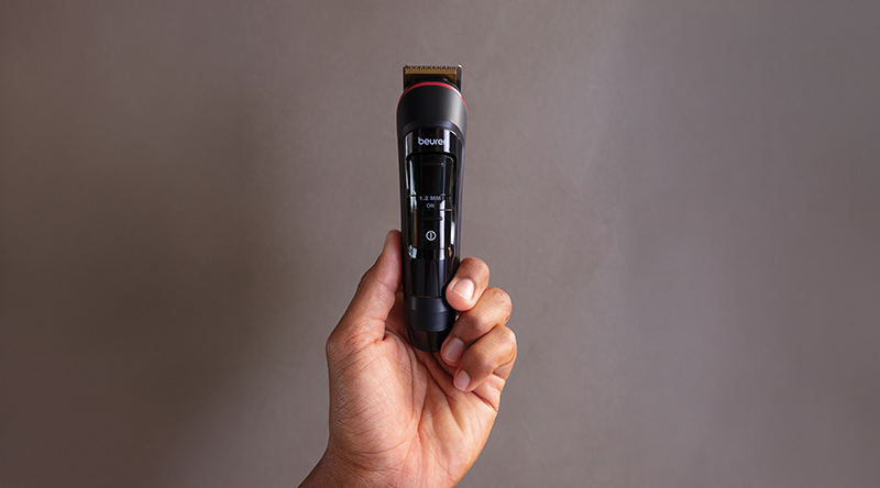 Hand hält den Beurer Bart Trimmer MN4X vor dunklem, neutralem Hintergrund 