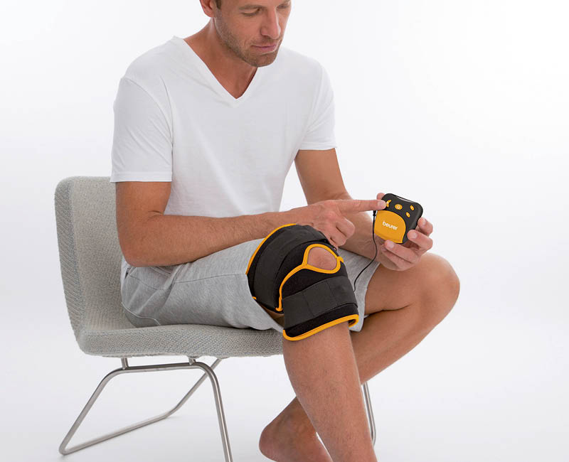 Beurer EM 29 EMS Gerät - Anwendungsbild Mann sitzt auf Stuhl und testet Gerät am Knie