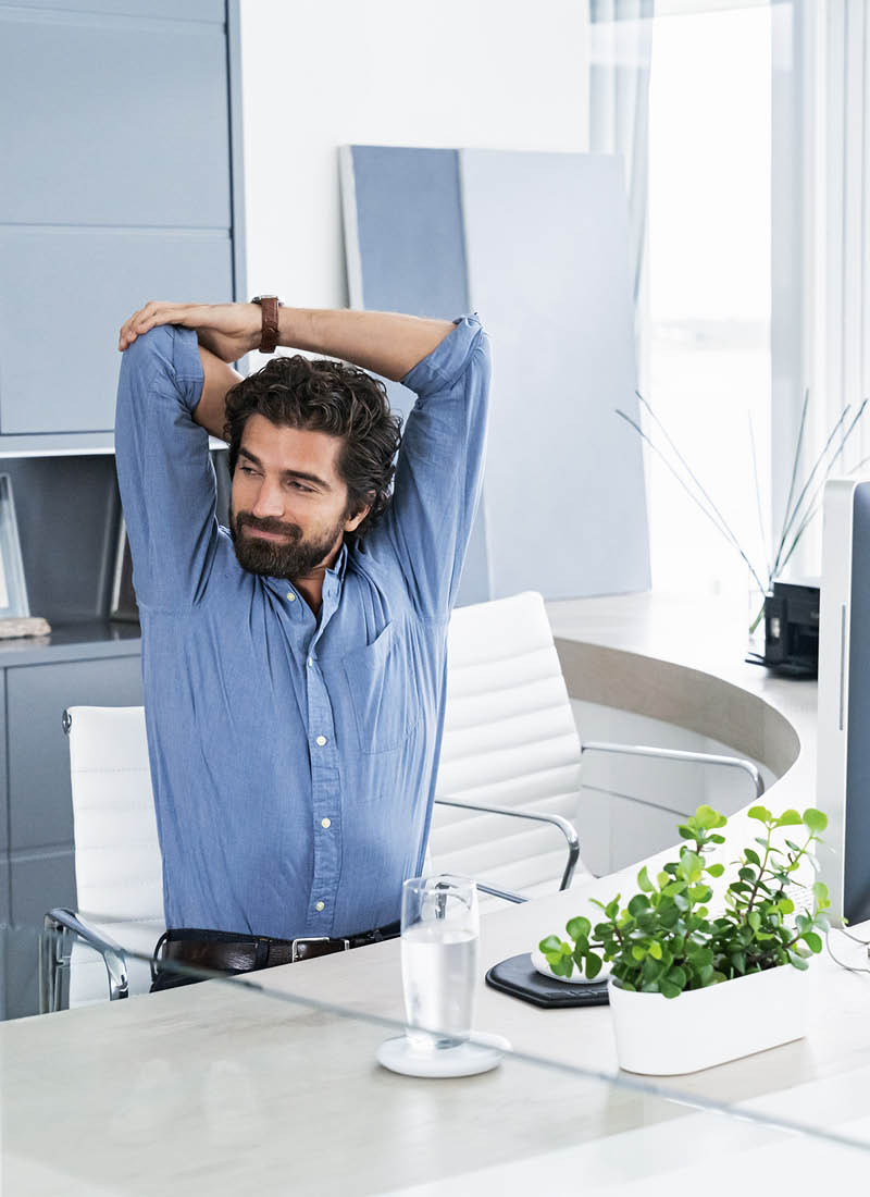 Mann sitzt auf einem Stuhl und dehnt seinen Rücken