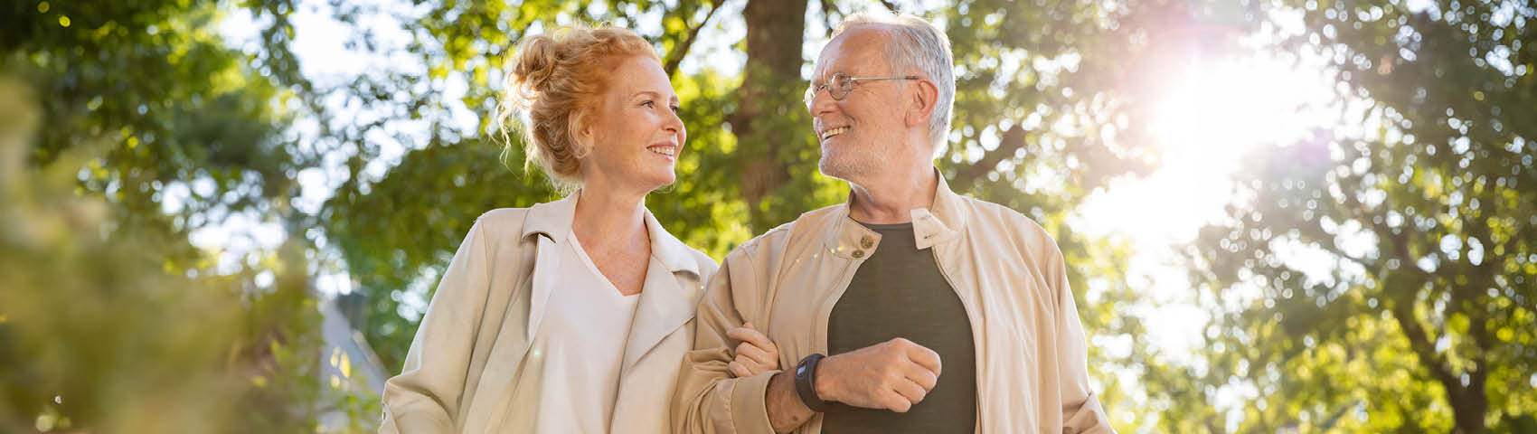 Älterer Mann und Tochter gehen Arm in Arm spazieren, der Mann trägt das Gardia Notrufarmband von Beurer