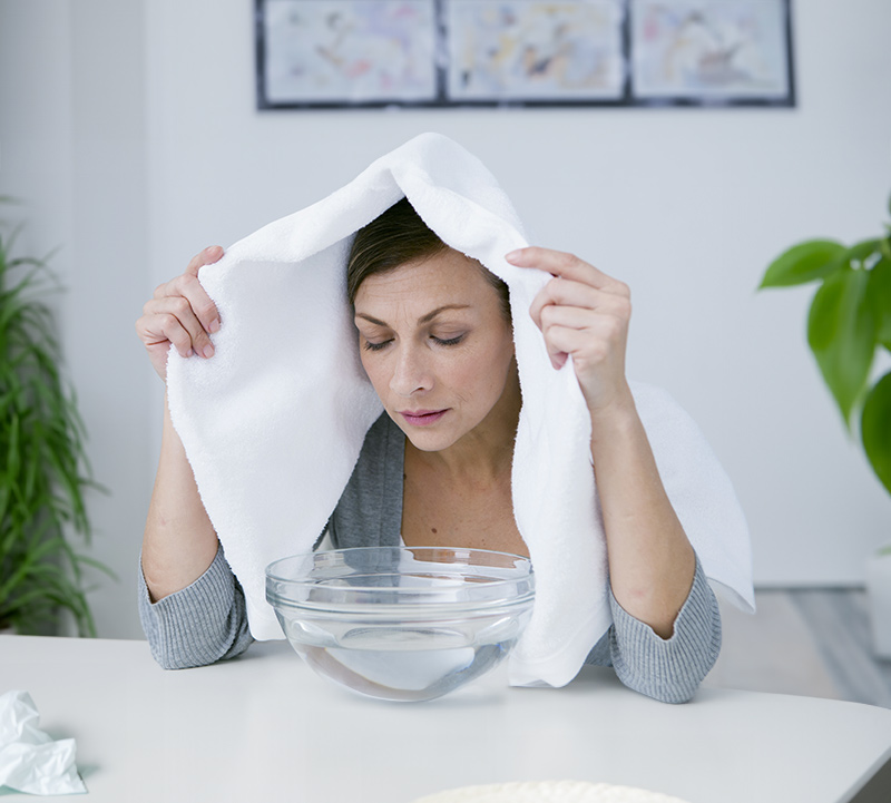 Frau inhaliert Dampf über Schüssel 