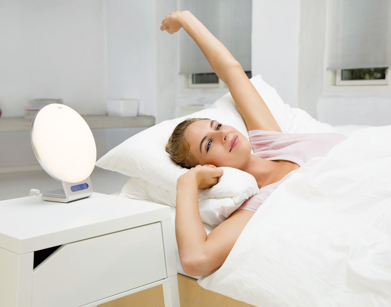 Frau wacht erholt im Bett auf mit dem Beurer Lichtwecker WL 75