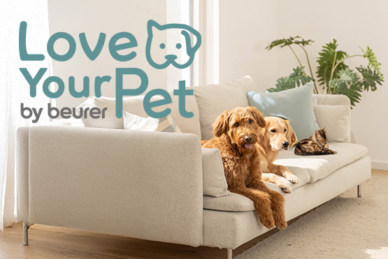 Zwei Hunde und eine Katze liegen auf einem Sofa. Daneben der Schriftzug "Love Your Pet by beurer"